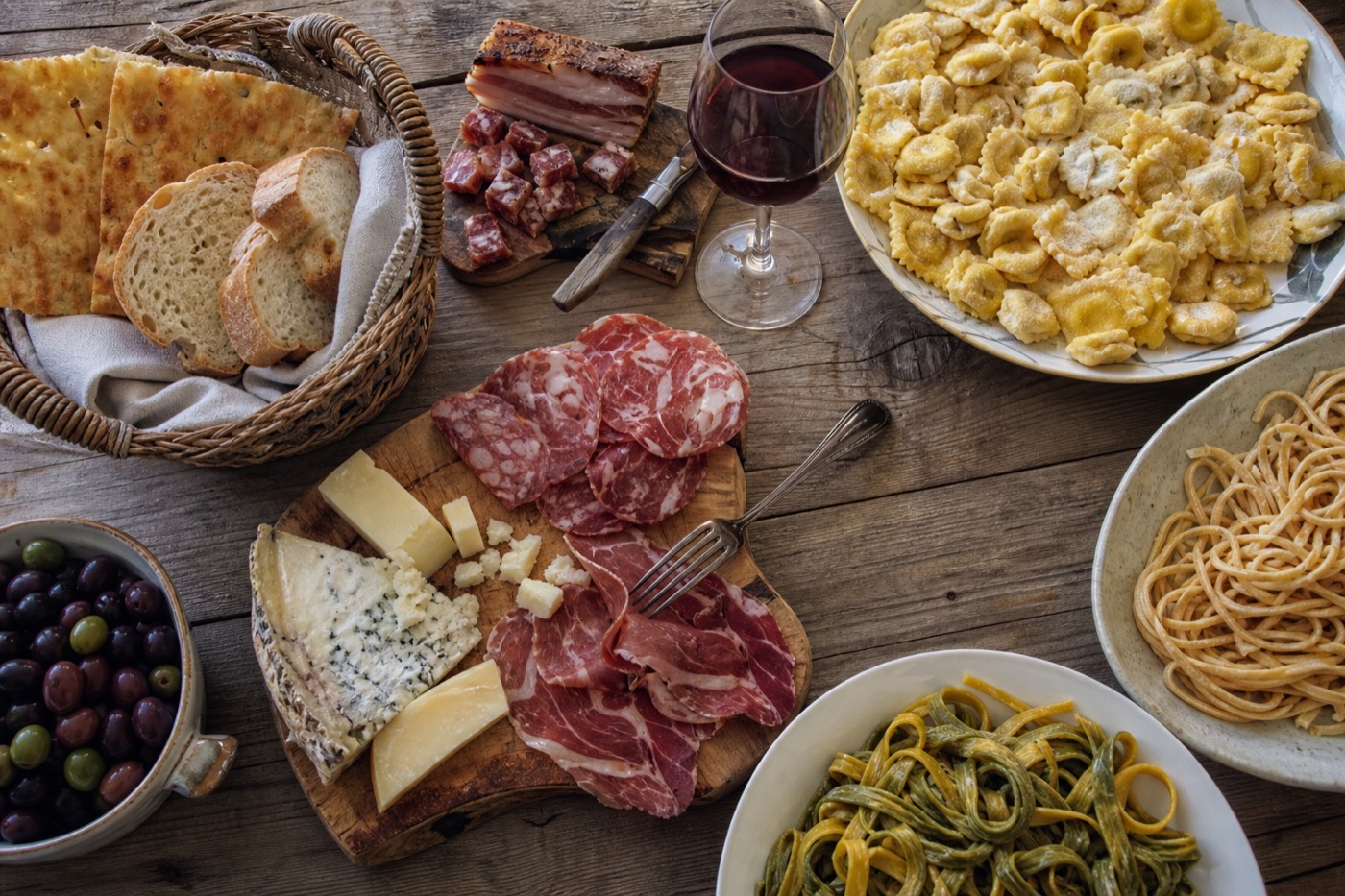 A specialty food shop window in Parma with Parmigiano wheels and ham, a stop on the best city in Italy for a food tour