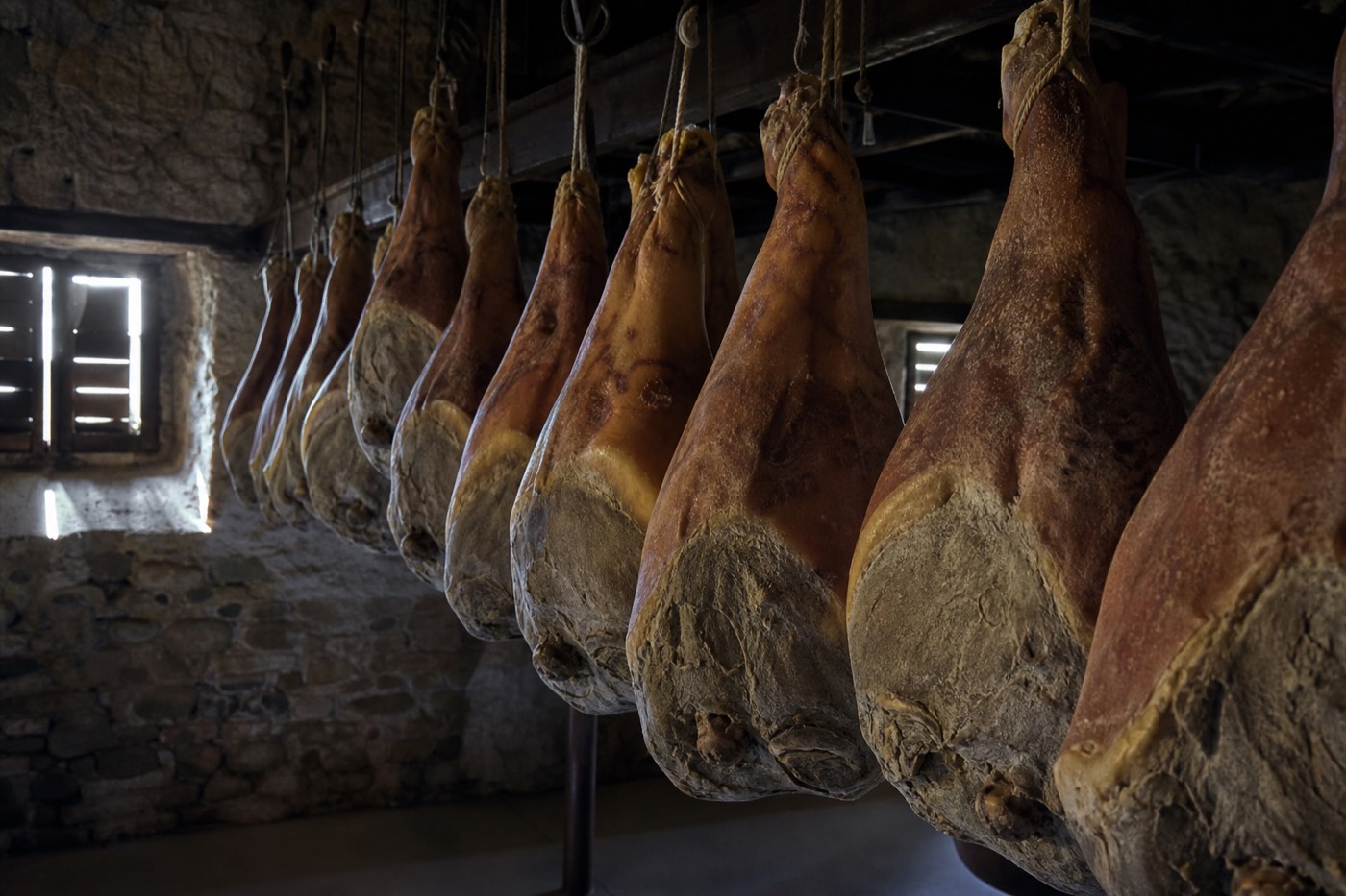 Rows of Prosciutto di Parma legs curing in an aging chamber near Langhirano, a highlight of Prosciutto di Parma ham tours